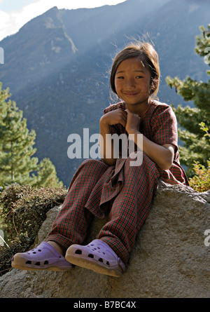 Porträt von einem freundlichen nepalesische Mädchen sitzt auf Felsen in Namche Bazar Dorf in Sagarmatha National Park Khumbu-Region Nepal Stockfoto