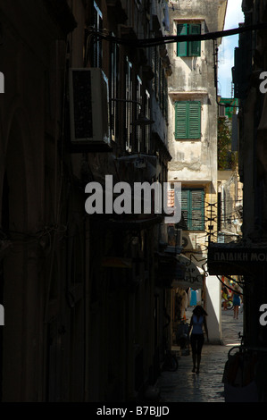 Eine Frau, die am 20. Januar 2009 durch eine enge historische Gasse mit hohen Gebäuden in Korfu Town auf Korfu Island, Griechenland, spaziert. Stockfoto