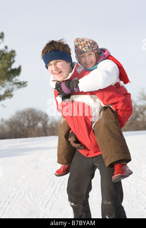 15 jährige Piggy-Backs 9 Jahre altes Mädchen, outdoor Winter, Winnipeg, Kanada Stockfoto