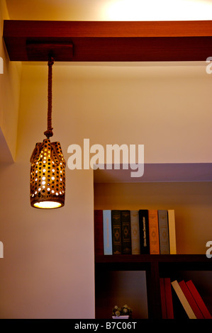 Eine moderne Lampe an der Decke vor dem schwarzen Regal mit Büchern Stockfoto