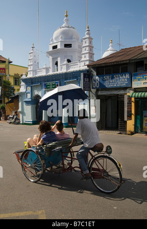 Touristen auf einem Tri-Shaw vor einer Moschee in Georgetown, Penang, Malaysia Stockfoto