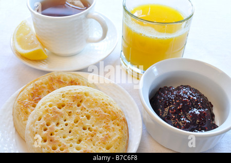 Eine Tasse schwarzer Tee mit Zitrone, Fladenbrot, Marmelade und Orangensaft auf weißem Hintergrund. Stockfoto