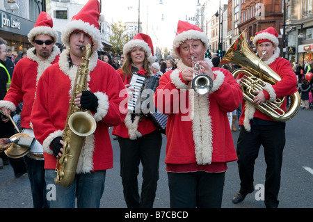 Musiker spielen auf der Oxford Street in London England UK Christmas Santa Claus-Outfits gekleidet Stockfoto