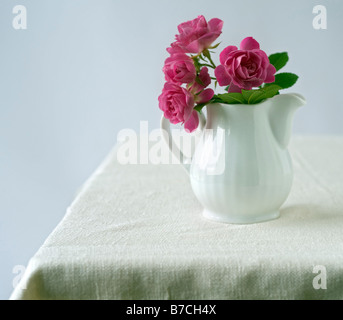 kleinen Rosenstrauß in einen Krug Keramik Milch Stockfoto