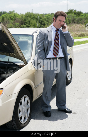 Ein Geschäftsmann auf der Straße mit einem flachen Reifen er seinen nächsten Termin zu sagen, dass er sich verspäten rufen s Stockfoto