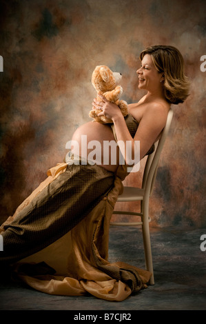 Schwangere Frau mit Kinderspielzeug in Sessel sitzend Stockfoto