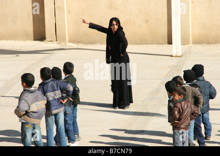 Muslimische Lehrerin in schwarz und verschleiert mit kurdischen Studenten in einer kleinen Dorfschule in der Nähe Amedi, Irak, Irakisch-Kurdistan, Dahuk, Stockfoto