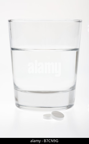 Glas halb voll leer mit Wasser mit zwei Paracetamol Tabletten isoliert auf weißem Hintergrund Stockfoto