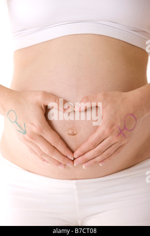 Nahaufnahme von Händen mit männlichen und weiblichen Symbolen auf ihnen in Form eines Herzens auf eine schwangere Frau s Bauch Stockfoto