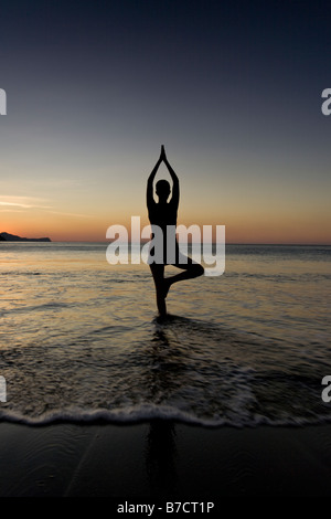 Silhouette der jungen Frau in Playas del Coco, Costa Rica Yoga am Strand bei Sonnenuntergang zu machen. Stockfoto