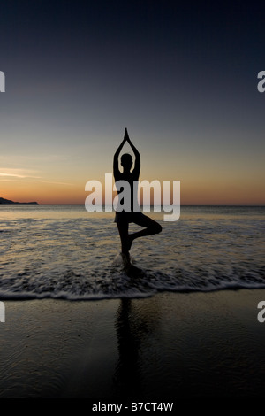 Silhouette der jungen Frau in Playas del Coco, Costa Rica Yoga am Strand bei Sonnenuntergang zu machen. Stockfoto