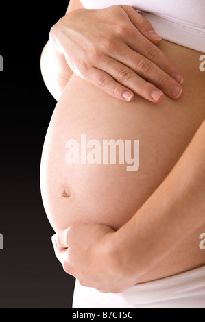 Schließen Sie sich einer schwangeren Frau die Hände um den Bauch Stockfoto