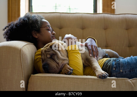 Eine junge Frau und ihre Shar-Pei ein Nickerchen auf der couch Stockfoto