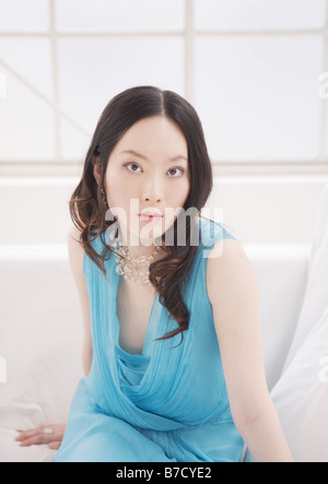 Frau im blauen Kleid auf sofa Stockfoto