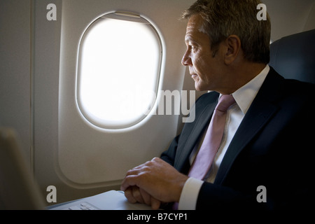 Ein Geschäftsmann, schaut aus dem Fenster eines Flugzeugs Stockfoto