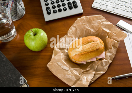 Ein Schreibtisch mit Büromaterial und ein Sandwich und ein Apfel drauf Stockfoto