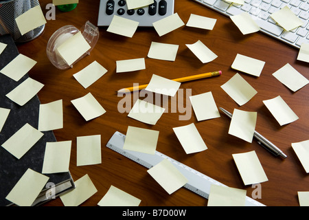 Ein Schreibtisch überladen mit Klebstoff Notizen und Büro Zubehör Stockfoto