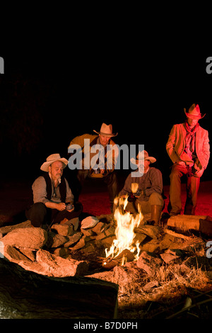 Cowboys sitzen um ein Lagerfeuer am Abend Stockfoto