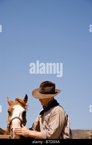 Ein Cowboy, ein Pferd zu streicheln Stockfoto