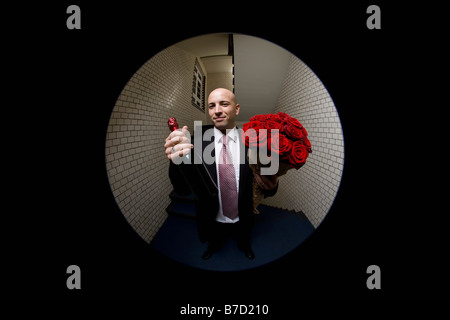 Ein Mann mit Rosen und Champagner, angezeigt durch ein Guckloch Stockfoto