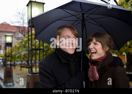 Junges Paar lachen unter einem Regenschirm Stockfoto