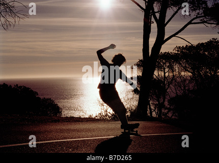 Silhouette eines Mannes, dem eine Skateboard auf einer Straße Stockfoto