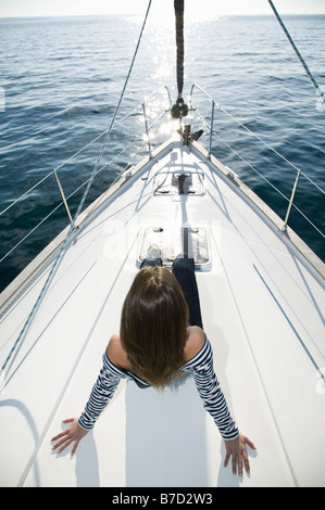 Eine Frau sitzt auf dem Vorschiff einer Yacht Stockfoto