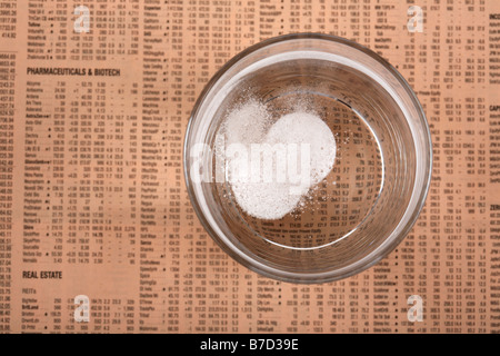 zwei lösliches Paracetamol Aspirin-Tabletten in einem Glas Wasser auf eine Kopie der financial times Stockfoto