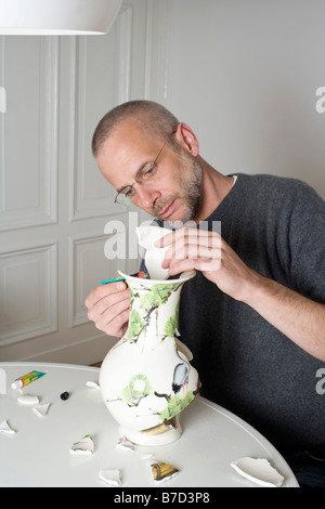 Ein Mann, eine zerbrochene Vase reparieren Stockfoto