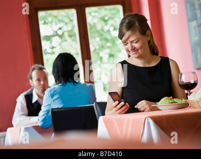 Frau am Telefon während des Essens Stockfoto