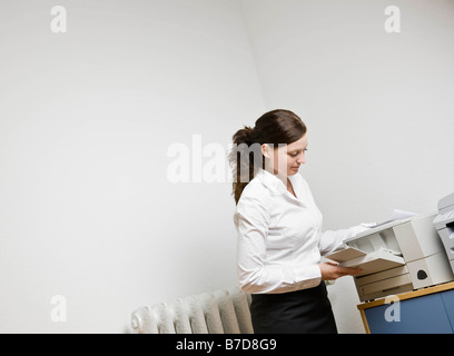 Frau, die einen Drucker mit Papier zu füllen Stockfoto