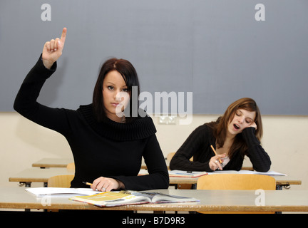 Schulmädchen, indem Sie ihre hand in der Klasse, während eine andere eine fast einschlafen Stockfoto