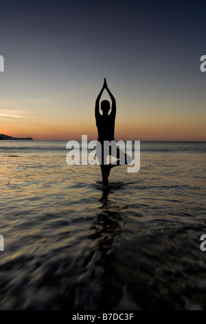 Silhouette der jungen Frau in Playas del Coco, Costa Rica Yoga am Strand bei Sonnenuntergang zu machen. Stockfoto