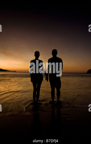 Paar Hand in Hand und beobachten den Sonnenuntergang am Strand in Playas del Coco, Costa Rica. Stockfoto