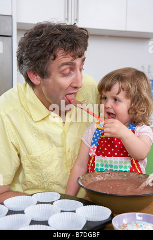 Tochter füttert Vater mit Teig Stockfoto