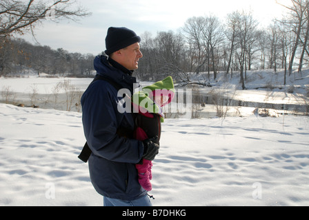 Ein Mann geht mit seiner kleinen Tochter durch den Schnee am Stadtpark in New Haven CT USA Stockfoto