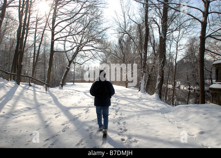 Mann zu Fuß durch den Schnee mit Sonne und Bäume Stockfoto