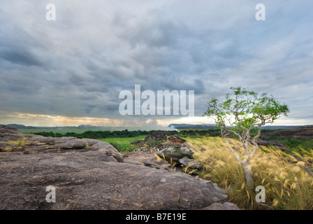 Touristen sitzen auf den Felsen des Ubirr mit einem Feuer im Hintergrund im Kakadu National Park Stockfoto