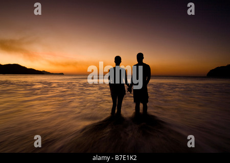 Silhouette des jungen Paares halten Hände am Strand bei Sonnenuntergang in Playas del Coco, Costa Rica. Stockfoto