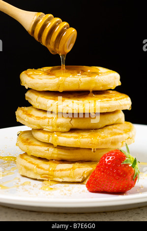 Honig in Strömen über Pfannkuchen Stockfoto