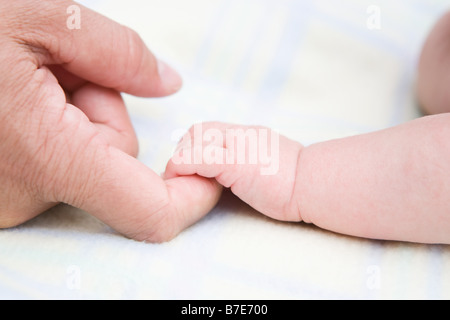 Baby mit Erwachsenen finger Stockfoto