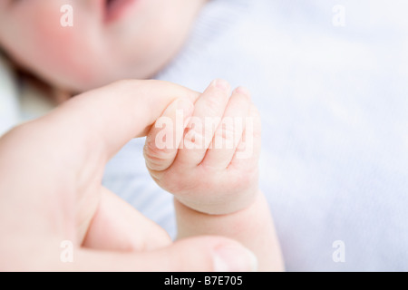 Baby mit Erwachsenen finger Stockfoto