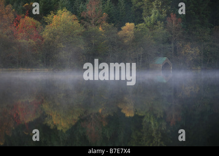 Morgendämmerung am Loch Ard. Die schönen Farben der Herbst, Morgennebel & Reflexionen der Bäume in dem vollkommen ruhig See gefangen Stockfoto