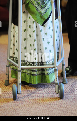 Eine ältere Dame Sikh wird an ihren Stuhl in eine multikulturelle zusätzliche Pflege nach Hause Bradford West Yorkshire geholfen. Stockfoto