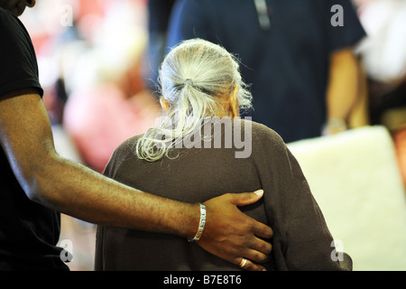 Eine ältere Dame Sikh wird an ihren Stuhl in eine multikulturelle zusätzliche Pflege nach Hause Bradford West Yorkshire geholfen. Stockfoto