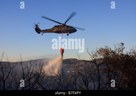 Sikorsky UH-60 Black Hawk Hubschrauber dumping Wasser auf Feuer. Stockfoto