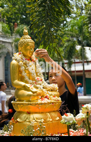 Kleiner Junge gießt Wasser über Buddha-Statue während Thai Neujahrsfeiern des Songkran - Wat Bowan Niwet Bangkok Thailand Stockfoto