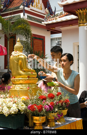 Junges Paar gießt Wasser über Buddha-Statue im thailändischen Neujahrsfest des Songkran - Wat Bowan Niwet Bangkok Thailand Stockfoto