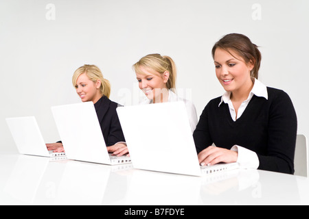 Ein Team von drei Geschäftsfrauen arbeiten auf weiße Laptops in einem modernen Ambiente sauber und frisch Stockfoto