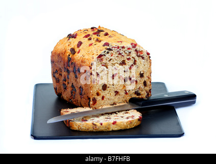 Hausgemachten Gourmet Brotlaib auf schwarze Schneidebrett mit Messer aufschneiden, isoliert auf weißem Hintergrund, Vollkorn Obst & Muttern. Stockfoto